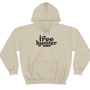 Puede incluir: Una sudadera con capucha beige con cord&oacute;n y bolsillo delantero. Las palabras "tree hugger" est&aacute;n impresas en negro, con letras estilizadas en el pecho. La sudadera con capucha est&aacute; hecha de un material suave y c&oacute;modo.