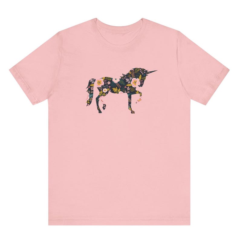 Puede incluir: Camiseta rosa claro con un dise&ntilde;o de unicornio floral. La silueta del unicornio est&aacute; llena de un patr&oacute;n de flores y hojas en tonos verdes, amarillos y rosas. La camiseta es de estilo cuello redondo cl&aacute;sico.