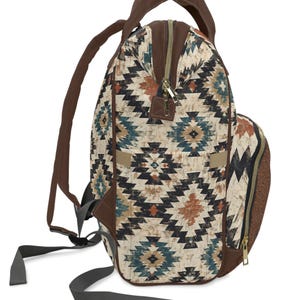May include: Backpack with a geometric pattern in shades of brown, teal, and black. The backpack has brown straps, a top handle, and a zipper closure. The bag has a side pocket and adjustable straps.