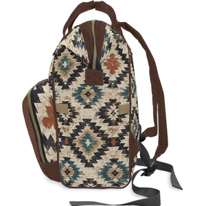 May include: A backpack with a Southwestern geometric pattern in shades of cream, brown, teal, and rust. The bag features brown straps, a top handle, and a zippered closure. The design includes a side pocket and adjustable shoulder straps.