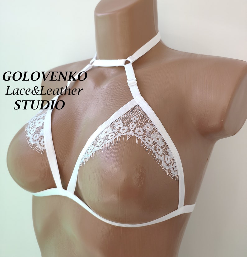 May include: White lace lingerie bra with adjustable straps and a choker neckline. The bra has a delicate floral pattern and is made of soft, sheer fabric.  GOLOVENKO Lace&Leather STUDIO.