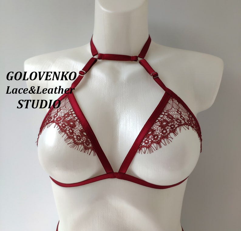 May include: Burgundy lace lingerie bra with adjustable straps and a choker style neckline. The bra has a delicate lace trim and is made of soft, stretchy fabric.  GOLOVENKO Lace&Leather STUDIO is printed on the bra.