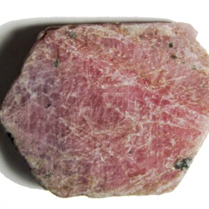 Peut inclure: Une pierre pr&eacute;cieuse de rubis rose brute avec une finition naturelle non polie. Le rubis a une forme l&eacute;g&egrave;rement irr&eacute;guli&egrave;re et une surface textur&eacute;e.
