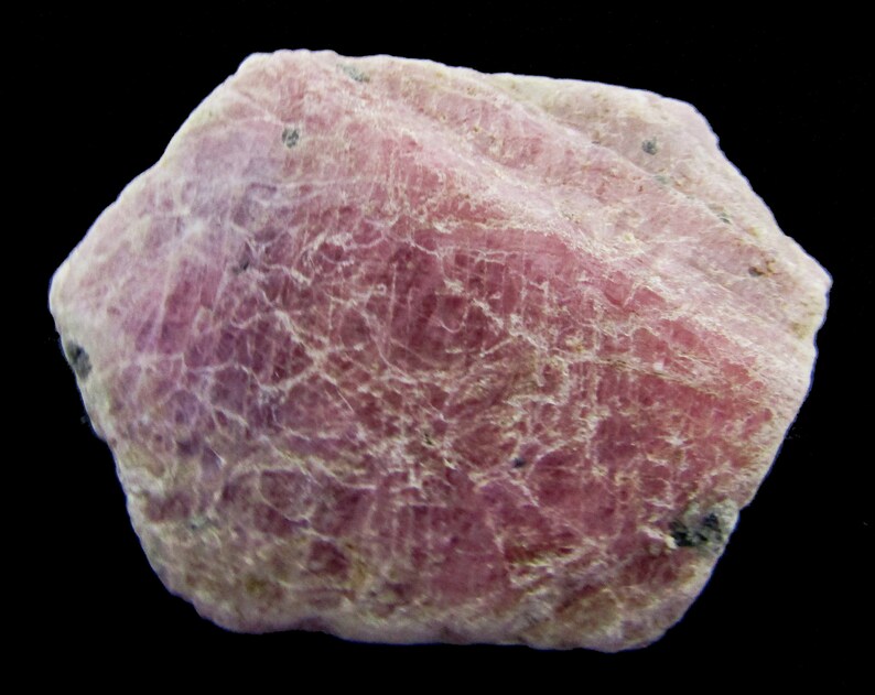 Peut inclure: Un cristal de rubis rose brut avec une surface textur&eacute;e. Le cristal est opaque et a une teinte l&eacute;g&egrave;rement violette.