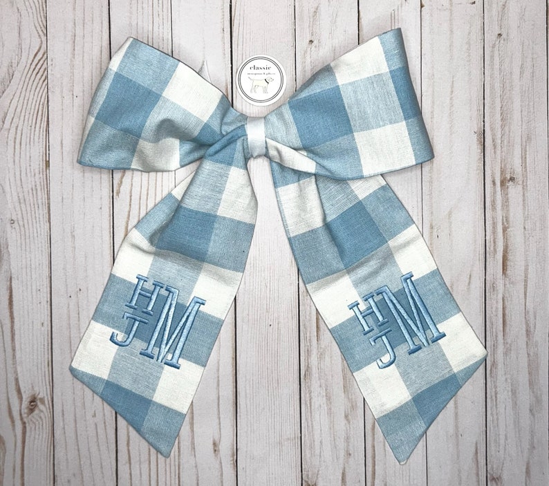 May include: A blue and white gingham bow with the monogram "HJM" embroidered on each side.