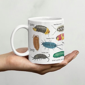 May include: White ceramic mug featuring illustrations of various pill bugs, each labelled with a name, including "Rubber ducky", "Powder blue", and "Giant green pill bug".
