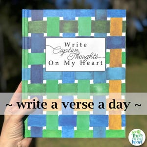 May include: A hardcover journal with a colorful woven pattern in blue, green, and gold. The cover features the text "Write Captive Thoughts On My Heart" and "write a verse a day". The journal is held by a hand.
