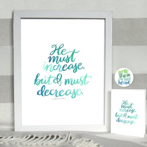 May include: A framed print with a white background and a teal, blue, and green gradient text that reads "He must increase, but I must decrease." The text is in a handwritten style. The quote is attributed to John 3:30. A small white card with a teal, blue, and green gradient text that reads "He must increase, but I must decrease." The text is in a handwritten style. The quote is attributed to John 3:30. A small white circle sticker with a green, yellow, and white gradient text that reads "write them on my heart" is in the upper right corner of the image.