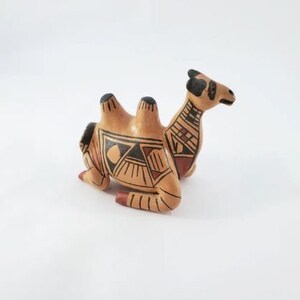 May include: A hand-painted ceramic camel figurine with black and brown geometric patterns on a tan background.