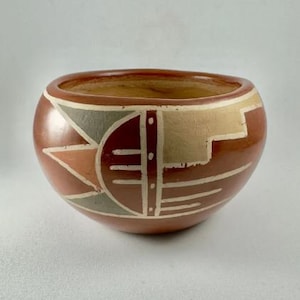 Może przedstawiać: Terakotowa miska z geometrycznym wzorem w odcieniach brązu, beżu i szarości. Miska ma zaokrąglony kształt i szeroki rant.