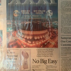 May include: A newspaper clipping from the January 25, 1997 edition of the Los Angeles Times, reporting on Super Bowl XXXI, with the headline "No Big Easy". The article discusses the Green Bay Packers and the New England Patriots, with a photo of the stadium in the background.