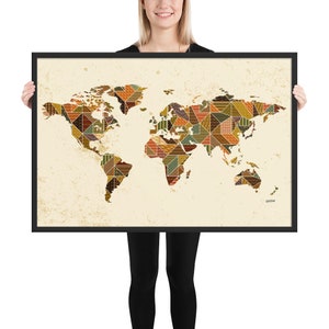 Op de afbeelding: Een ingelijste wereldkaartprint met een patchwork-ontwerp in tinten bruin, oranje, geel en groen. De kaart is op een crèmekleurige achtergrond met een verweerde textuur.