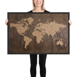 May include: A framed world map made of small, brown, circular pieces of wood on a dark brown wooden background.