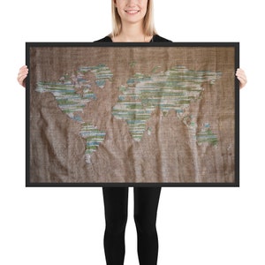 May include: A framed world map embroidered on a brown canvas with green, blue, and white thread. The map is slightly wrinkled and has the word "BASIN" in the bottom right corner.