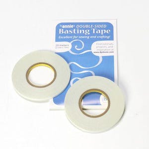 May include: Two rolls of double-sided basting tape with a backing card. The tape is light green with a yellow and brown center. The backing card is white and blue and reads "DOUBLE-SIDED Basting Tape" and "Excellent for sewing and crafting!"