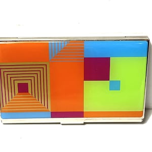 May include: A rectangular metal case featuring a vibrant geometric design on the front. The pattern consists of blocks of orange, lime green, light blue, and magenta, with a series of thin lines forming a square spiral on the left side.