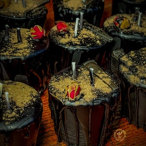 May include: A group of black candles with gold glitter and dried rose petals on top. The candles are arranged in a circle on a wooden surface.