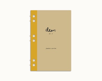 May include: A brown notebook with a yellow spine. The cover has the word "dear" written in black cursive and the text "pt. 2" below it. The text "jasmine carrine" is printed in black below the word "dear".