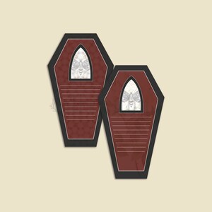 May include: Two red coffin-shaped note cards with black borders and a white moth design in the center of each card.