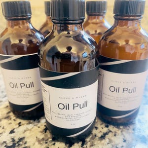 May include: Several amber-colored glass bottles with black caps and white labels. The labels read "Oil Pull" and list benefits. Each bottle contains 4 fl oz of product.