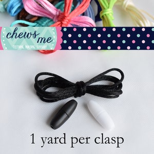 May include: Black cord with a black and white plastic clasp. The cord is 1 yard long. "Chews Me Teething, Nursing, Sensory" is written on a pink and blue banner with white polka dots.