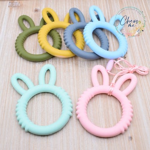 May include: A set of six silicone teethers in various colors, shaped like a bunny with ears. The teethers are designed for babies and toddlers to help soothe sore gums.