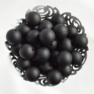 May include: A bowl filled with black silicone beads. The beads are round and have a matte finish.