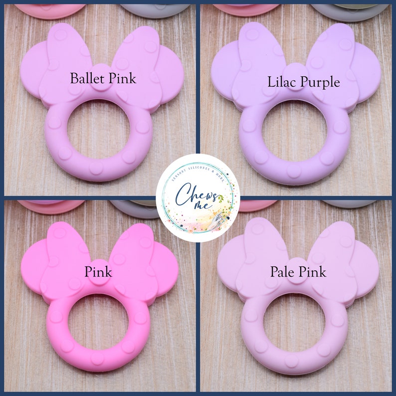 K&ouml;nnte beinhalten: Vier Silikon-Bei&szlig;ringe in Form eines Minnie Mouse-Kopfes mit Schleife. Die Bei&szlig;ringe sind in den Farben Balletrosa, Lila, Rosa und Hellrosa.