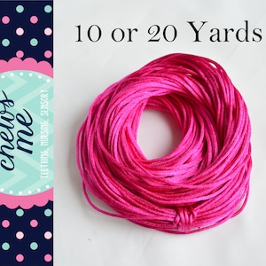 May include: A spool of bright pink cord, 10 or 20 yards, for crafting, jewelry making, or sensory toys.