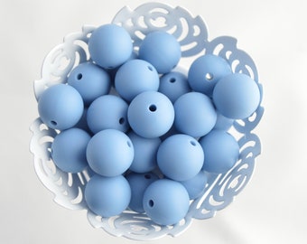 May include: A bowl filled with light blue silicone beads. The beads are smooth and round, and they are perfect for making jewelry or other crafts.
