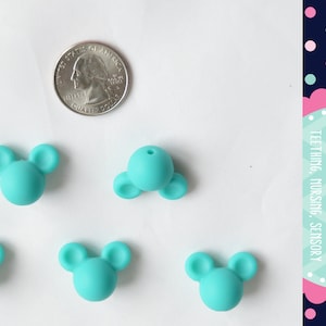May include: Five turquoise silicone teether beads shaped like Mickey Mouse heads. The beads are about the size of a US quarter.