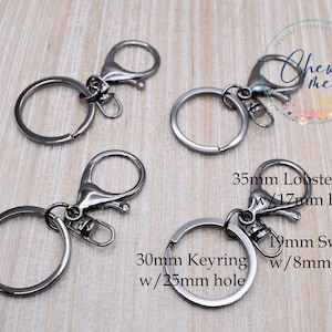 May include: Four silver keychains with different styles and sizes. The keychains include a 35mm lobster clasp with a 17mm hole, a 30mm keyring with a 25mm hole, and a 19mm swivel with an 8mm hole.