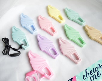 May include: A set of ten pastel-colored silicone ice cream cone teethers with a hole for a cord. The teethers are arranged in a row on a white surface. The teethers are in the following colors: light blue, pink, light green, purple, yellow, light green, beige, light blue, pink, and light green.