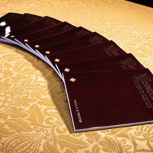 May include: A stack of burgundy-colored books with gold lettering on the spines. The top book has the title "Vestments" and the text "A Guide to Their Use".