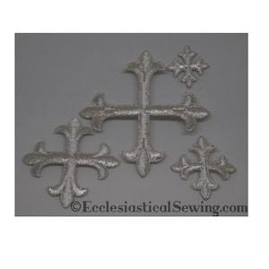 Könnte beinhalten: Fünf silberne gestickte Kreuze in verschiedenen Größen. Die Kreuze haben an den Enden jedes Arms ein Fleur-de-lis-Design. Die Kreuze befinden sich auf einem grauen Hintergrund. ©EcclesiasticalSewing.com
