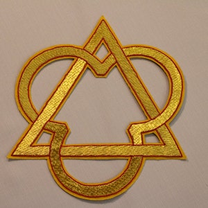 以下が含まれることがあります： 三角形とハートの形をした金色の刺繍パッチ。パッチは赤で縁取られています。
