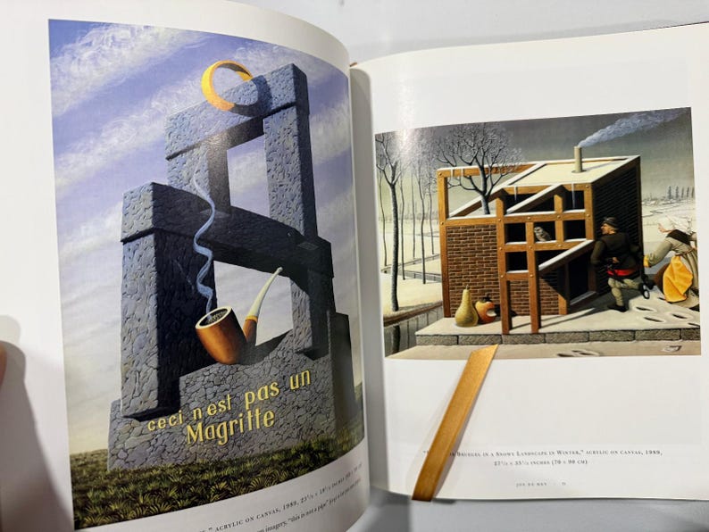 May include: A double-page spread featuring a surrealist painting with a stone structure, a pipe, and the text "ceci n'est pas un Magritte." The artwork includes a yellow crescent and a winter scene.