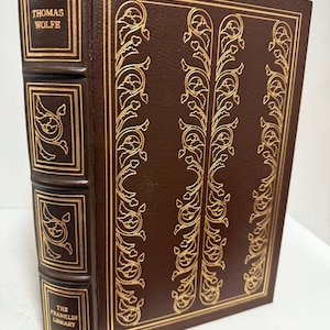 May include: A brown leather-bound book with gold lettering on the spine. The spine reads "Thomas Wolfe" and "The Franklin Library".