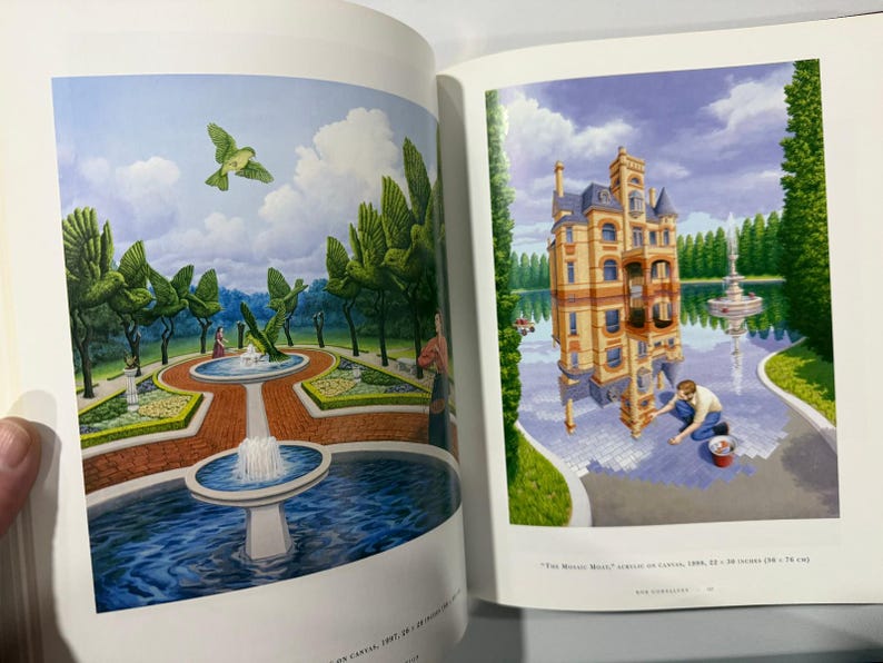 May include: A book spread with two surrealist paintings. One shows a garden with bird-shaped topiary and a fountain. The other depicts a building reflected in water, with a person painting the reflection.