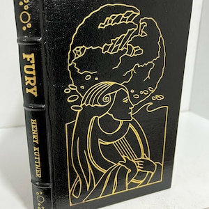 Op de afbeelding: Een zwart lederen gebonden boek met gouden letters op de rug. De titel is "Fury" door Henry Kuttner. De omslag toont een gouden illustratie van een vrouw die een lier bespeelt.