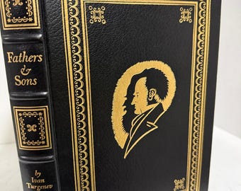 Puede incluir: Un libro de tapa dura negro titulado Fathers & Sons de Iván Turguénev. La portada presenta una silueta dorada de un hombre de perfil rodeada por un borde decorativo. El lomo incluye letras doradas y patrones geométricos ornamentados.