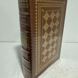 May include: A brown leather-bound book with gold accents and a title that reads "An Independent Man" by James M. Ford. The book is wrapped in plastic.