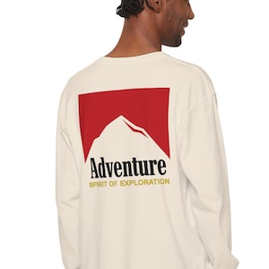 May include: A white long-sleeve t-shirt with a red square on the back. The square has a white mountain silhouette and the text "Adventure Spirit of Exploration" in black and gold.