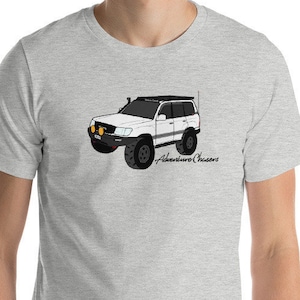 May include: A gray t-shirt with a white cartoon illustration of a Land Cruiser with a roof rack. The text "Adventure Chasers" is printed below the car.