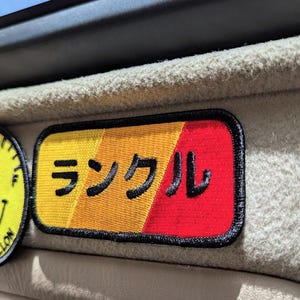May include: A yellow, orange, and red embroidered patch with the Japanese word "シンクル" (single) in black.