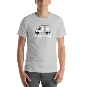 May include: A grey t-shirt featuring a white silhouette of a van with a ladder on top. The text "ADVANTURE" is printed below the van.