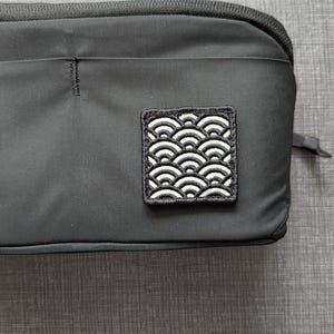 May include: A white ceramic mug with a black handle and the text "But First, Coffee" in a bold, black font. The mug is set against a blurred background, suggesting a cozy setting.