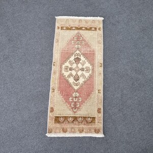 May include: A pink and beige runner rug with a traditional floral pattern. The rug has a fringe border and is made of wool.