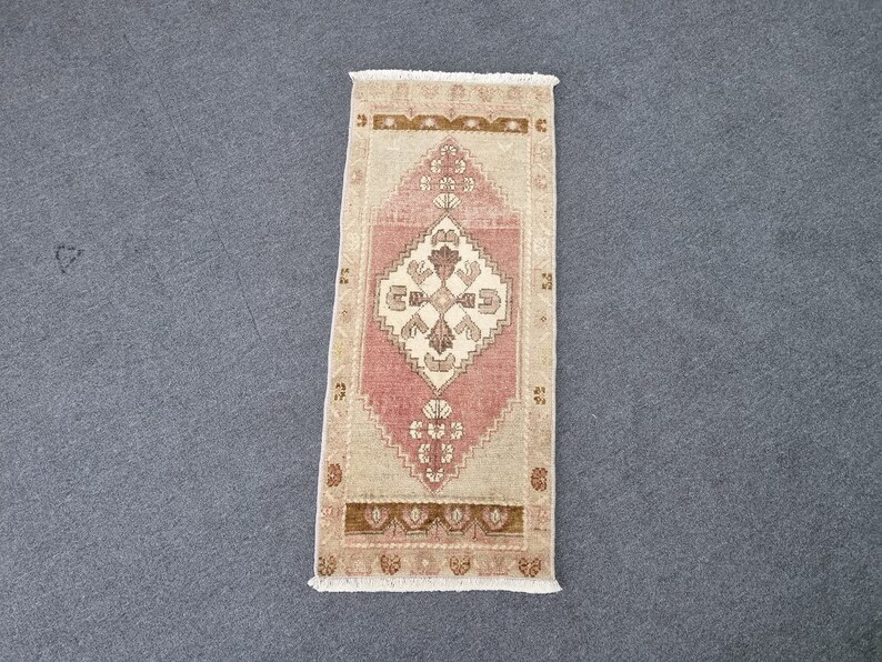 May include: A pink and beige runner rug with a traditional floral pattern. The rug has a fringe border and is made of wool.