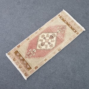 May include: A pink and beige runner rug with a traditional floral pattern. The rug has a fringed edge and is made of wool.